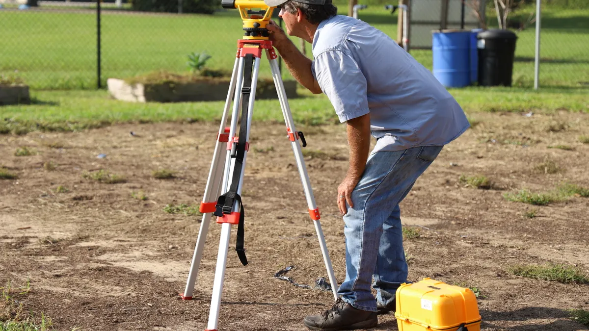 Worker adjusting a surveying instrument on a tripod